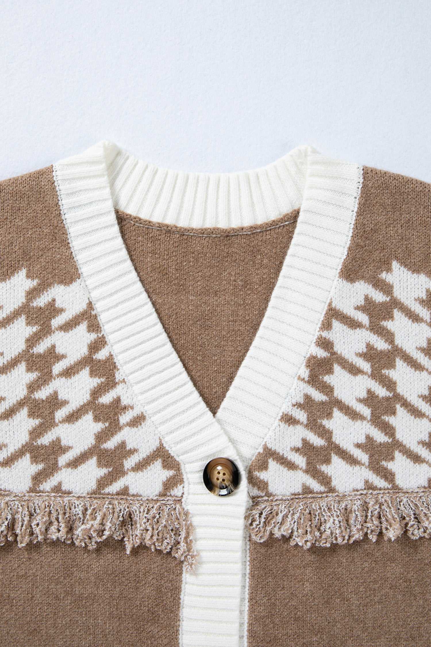 Close-up of khaki houndstooth knit cardigan neckline with white ribbed trim and button detail. Soft knit texture for fall layering.