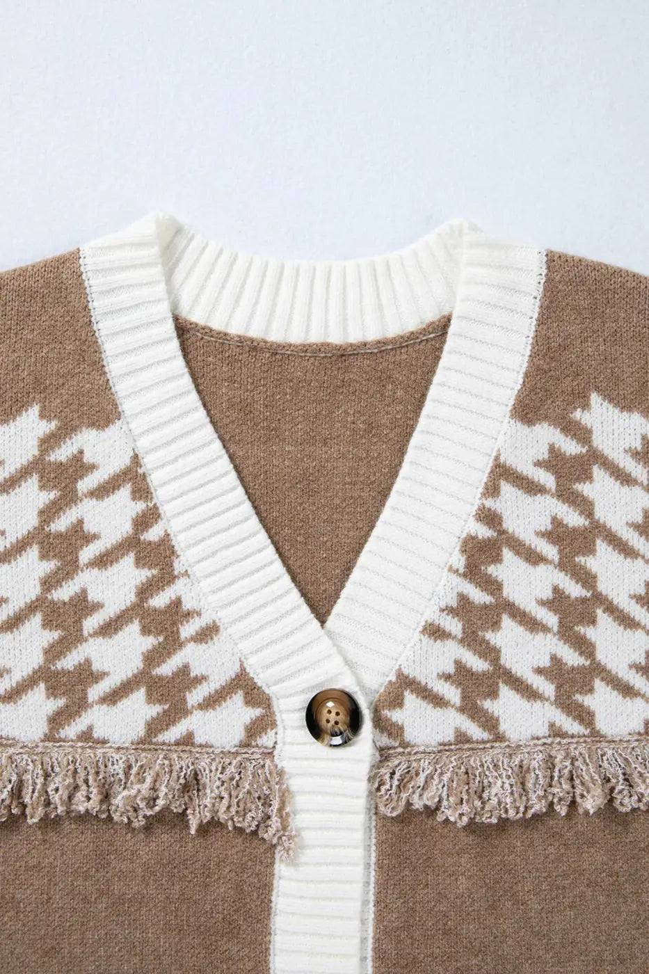 Close-up of khaki houndstooth knit cardigan neckline with white ribbed trim and button detail. Soft knit texture for fall layering.