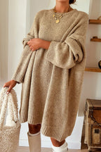 Person wearing a Khaki oversized jumper dress front view holding a matching handbag indoors.