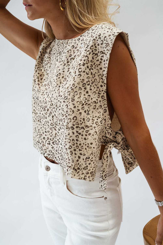 Apricot leopard knit tank top with side tie detail, sleeveless cut, and cropped fit, styled with high-waisted white jeans for summer wear.
