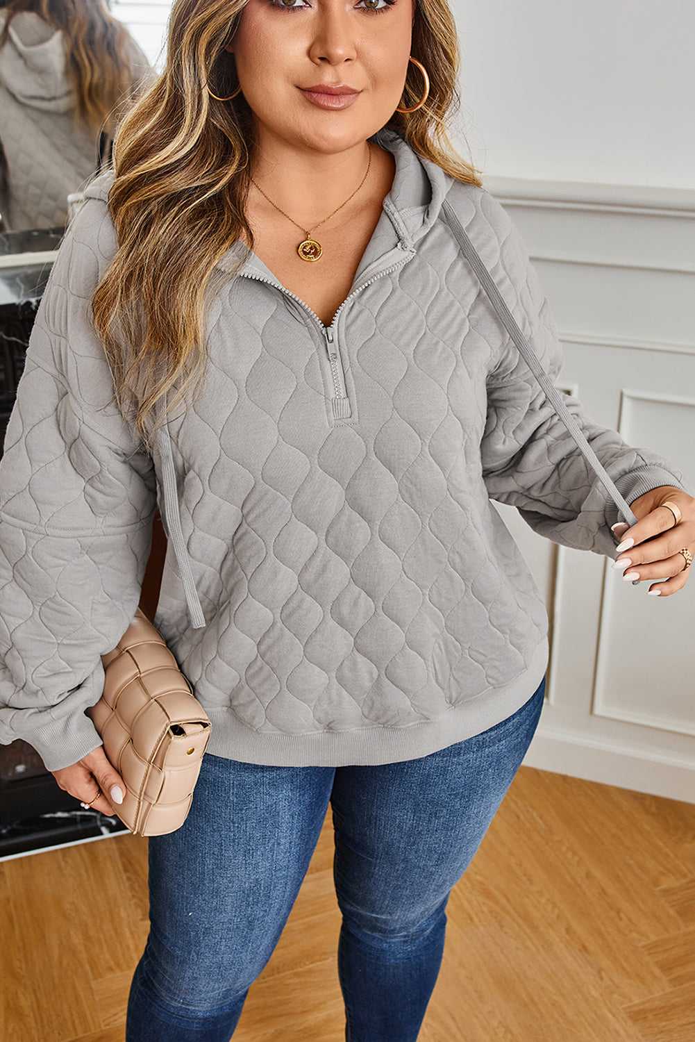 Plus size woman wearing curve grey quilted quarter-zip hoodie with jeans, showcasing soft quilted fabric and casual winter style.