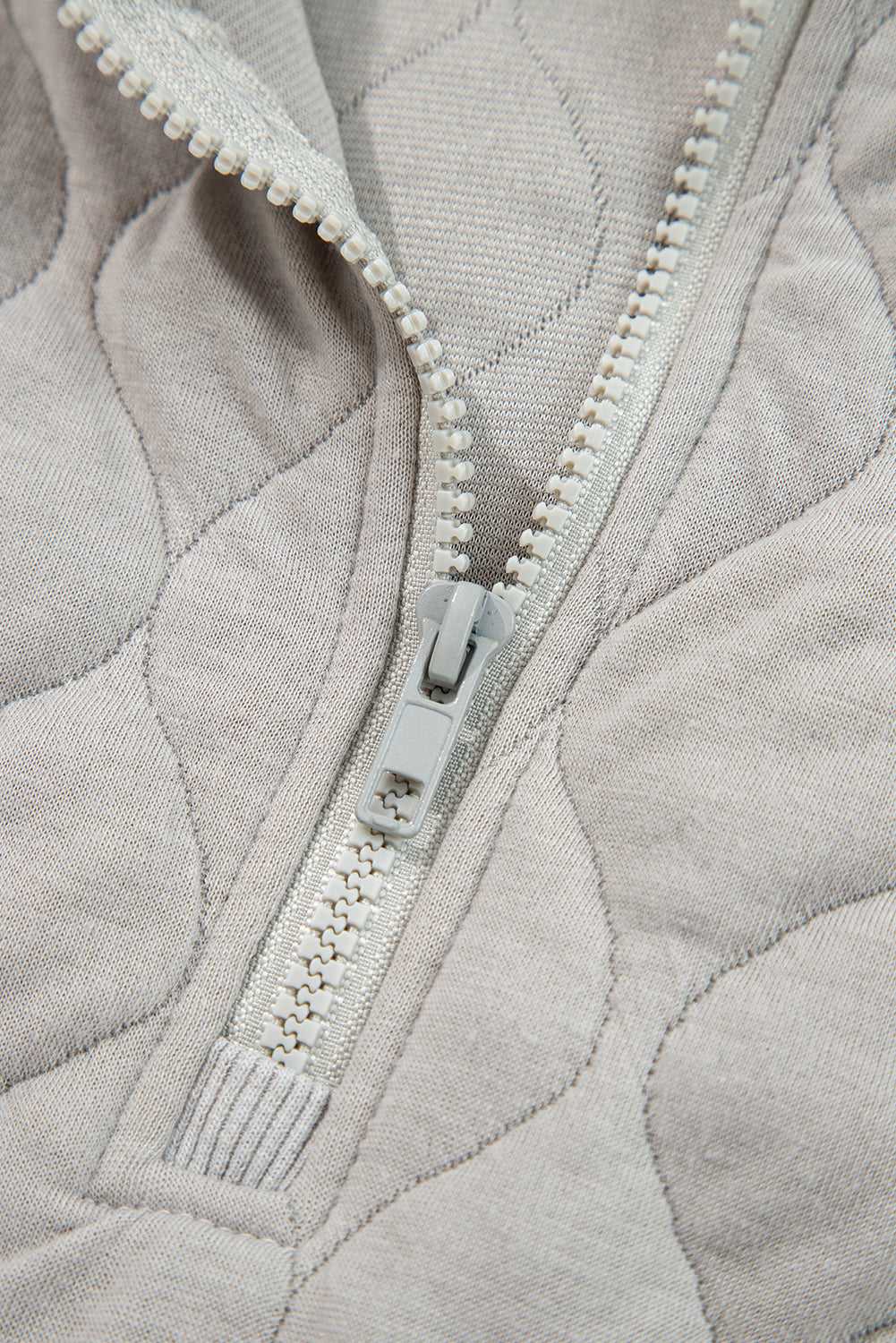 Close-up of zipper on curve grey quilted quarter-zip hoodie, highlighting quality stitching and durable hardware for everyday wear.