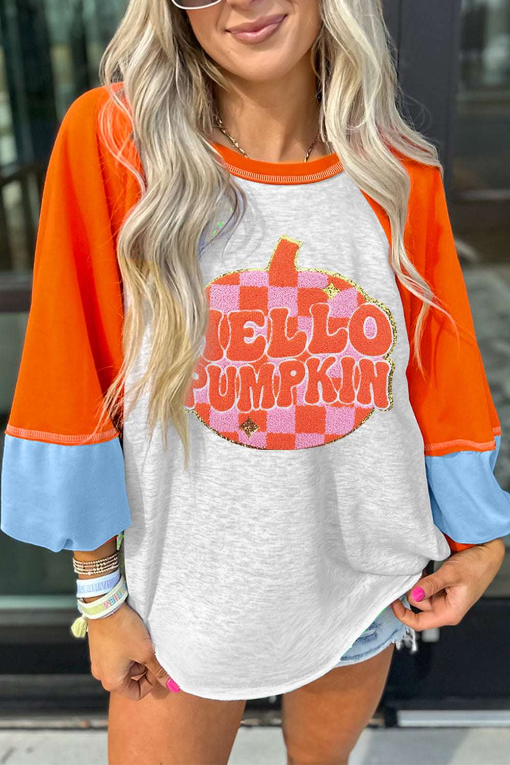 Cozy Hello Pumpkin sweatshirt with playful pumpkin graphic, orange and blue color-block sleeves, perfect for casual fall outfits.