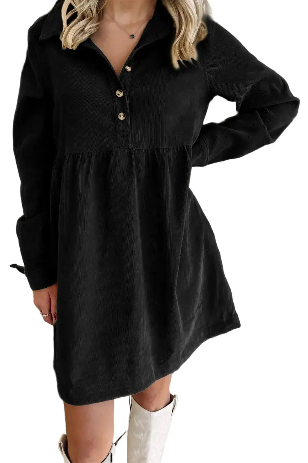 Person wearing a black dress with long sleeves against a brick wall.