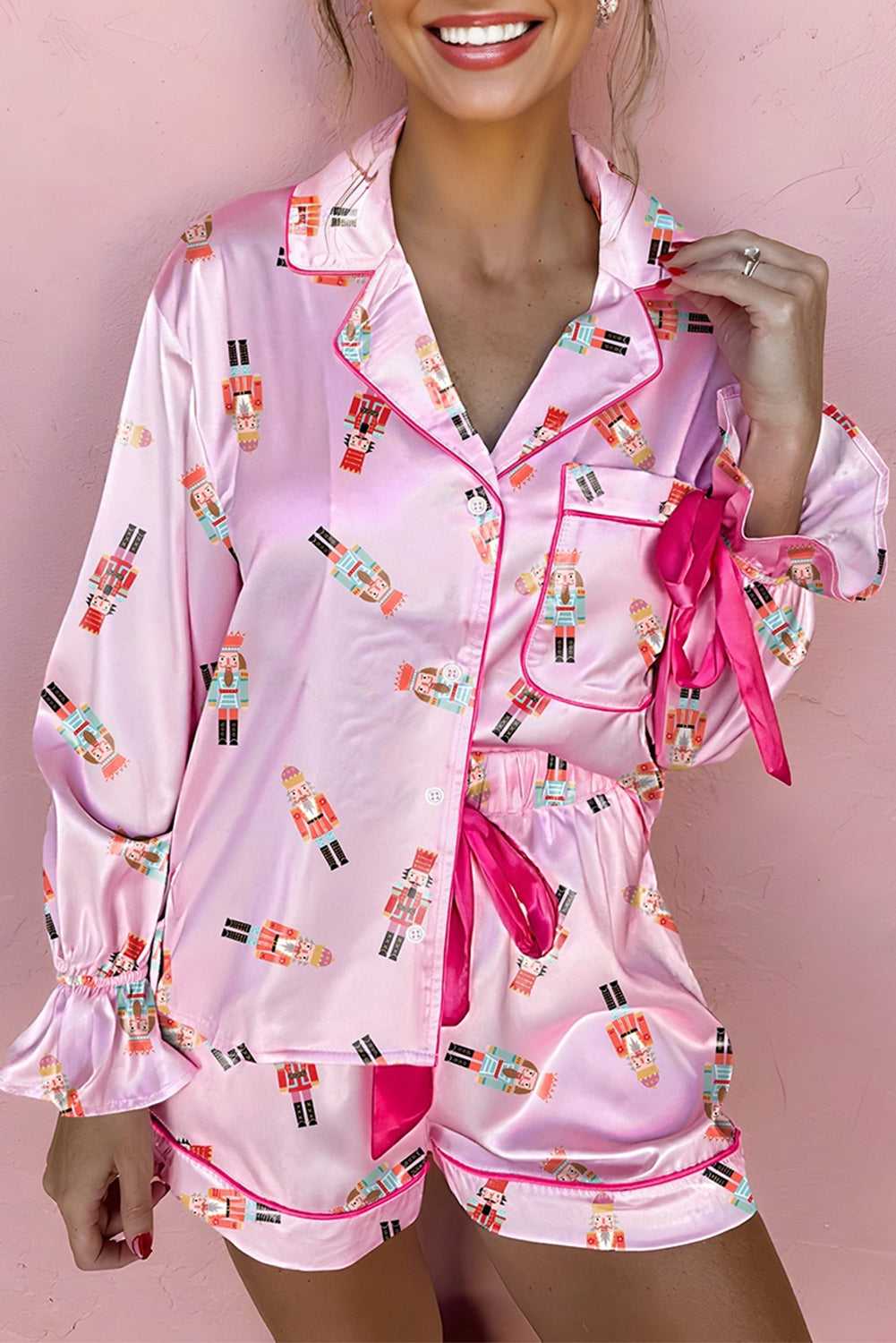 Model wearing pink satin Nutcracker pyjama set with bow detail and contrast trim