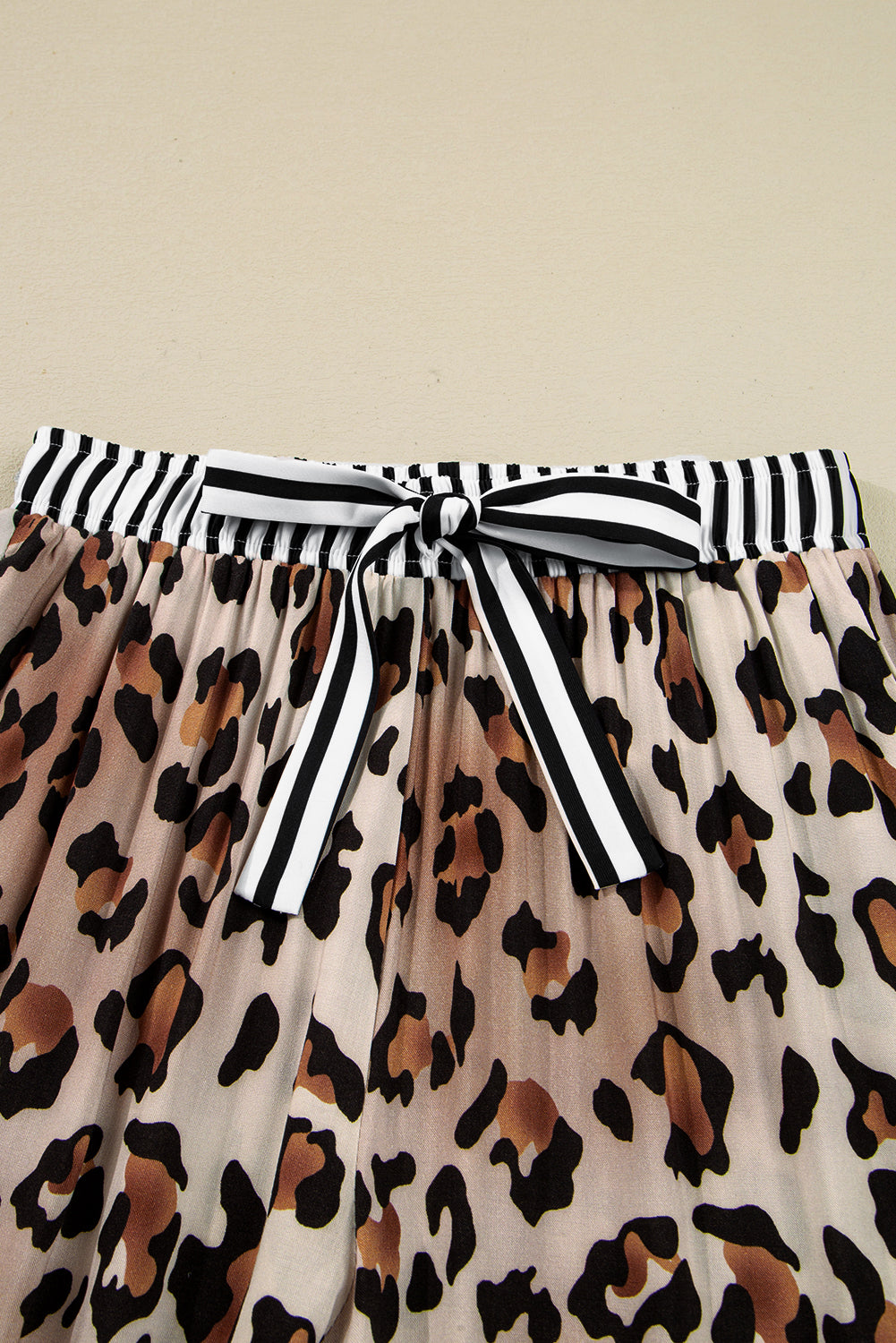 Leopard print wide‑leg pants in soft viscose with a striped belt on a beige background