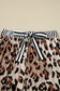Leopard print wide‑leg pants in soft viscose with a striped belt on a beige background