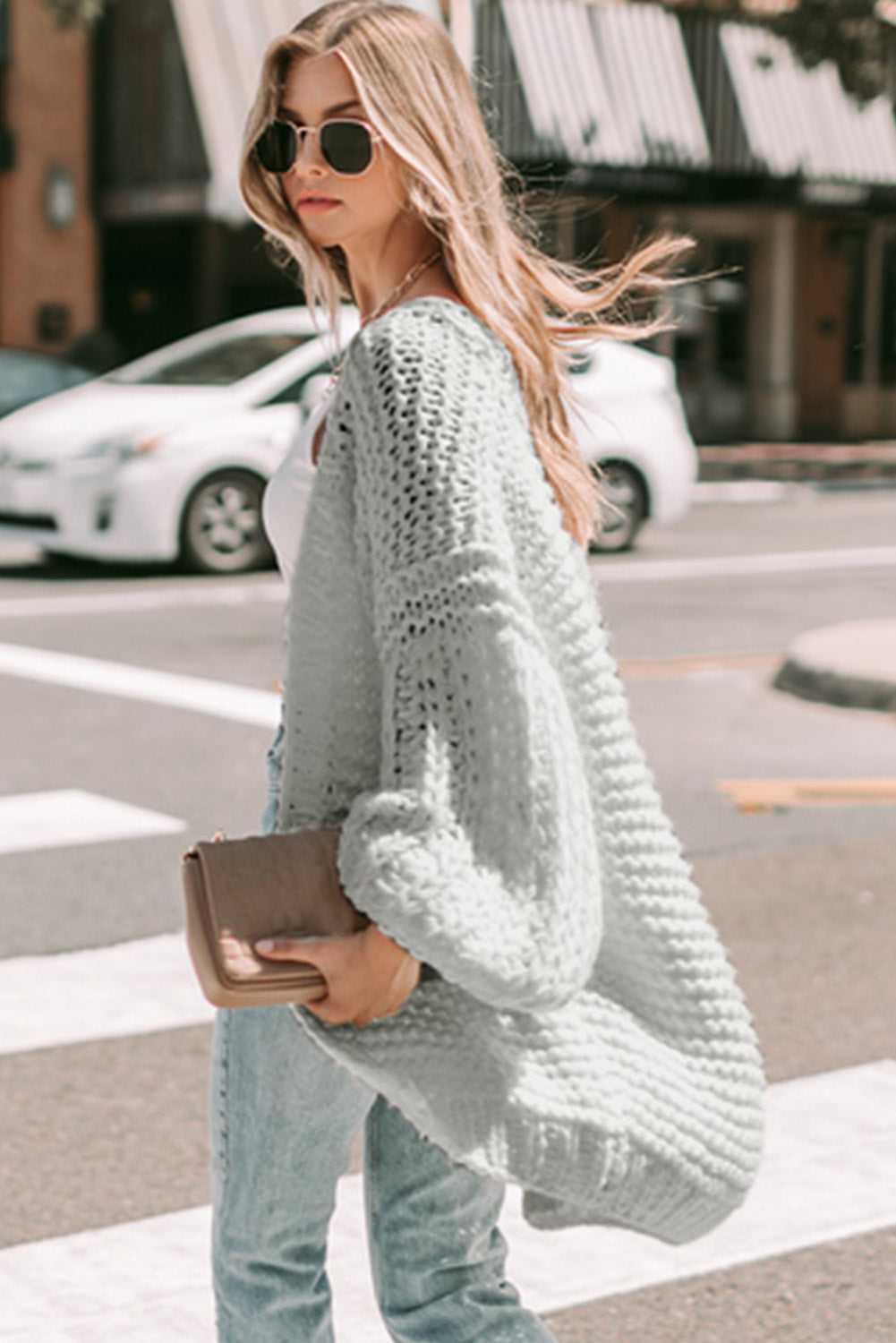 Side view of light grey oversized cardigan in chunky knit, ideal for layering in autumn street style looks.