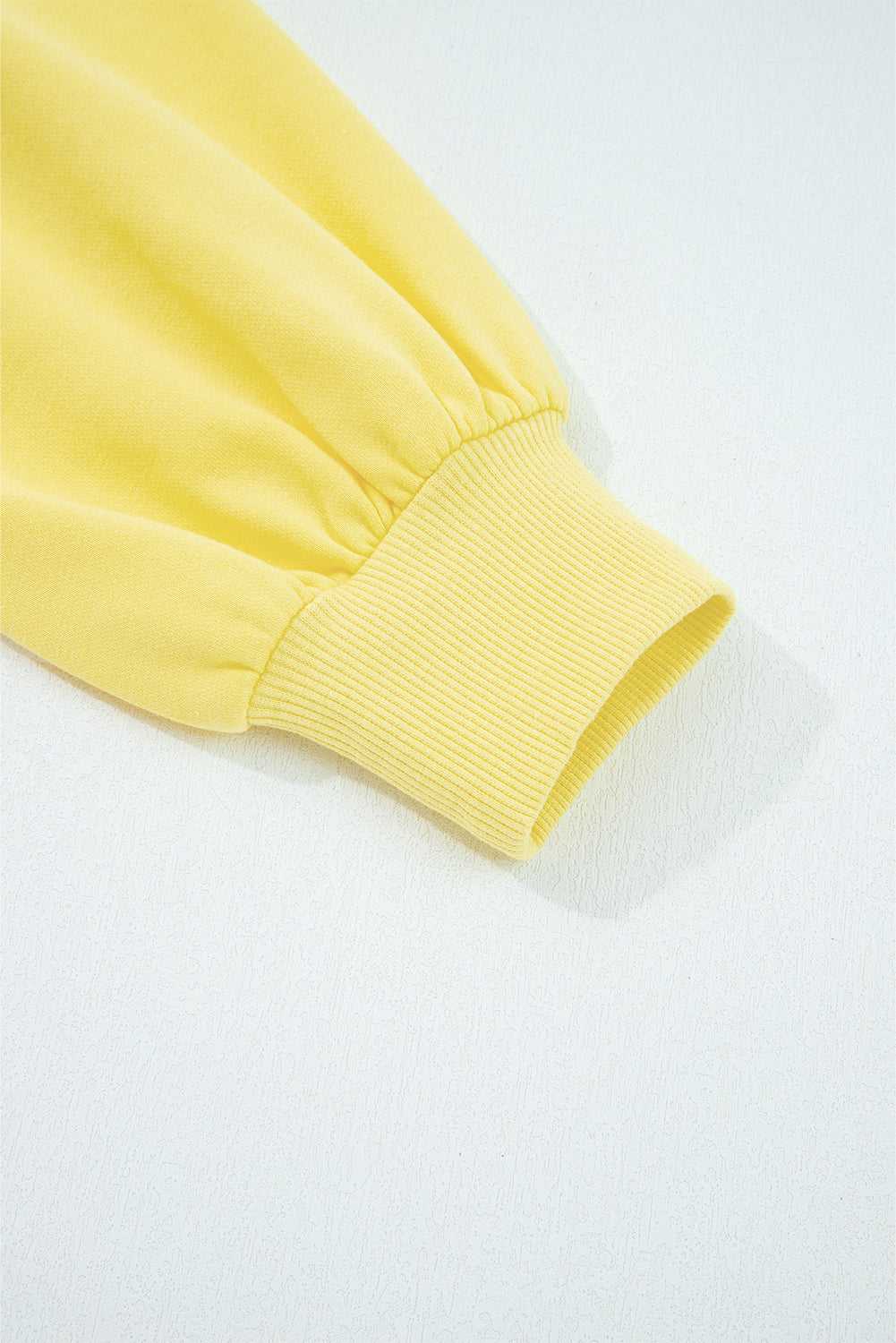 Close-up of yellow Drop Crop Set sleeve cuff with ribbed finish, emphasizing casual style and snug fit.
