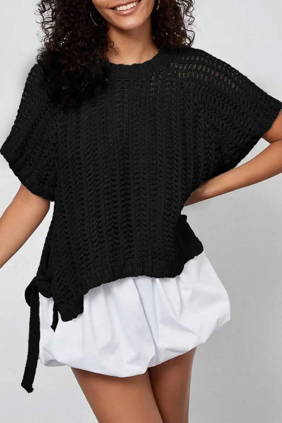 Plus Size Bow Tie Open‑Knit Jumper for Women in black with short sleeves and side bow detail, styled casually with white shorts.
