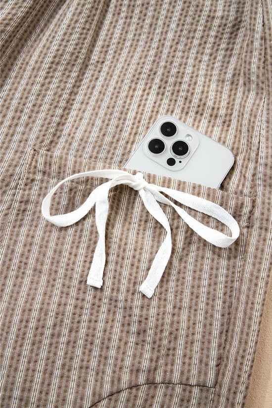 Detail of side cargo pocket on Brown Stripe Joggers with white bow tie and smartphone inside.