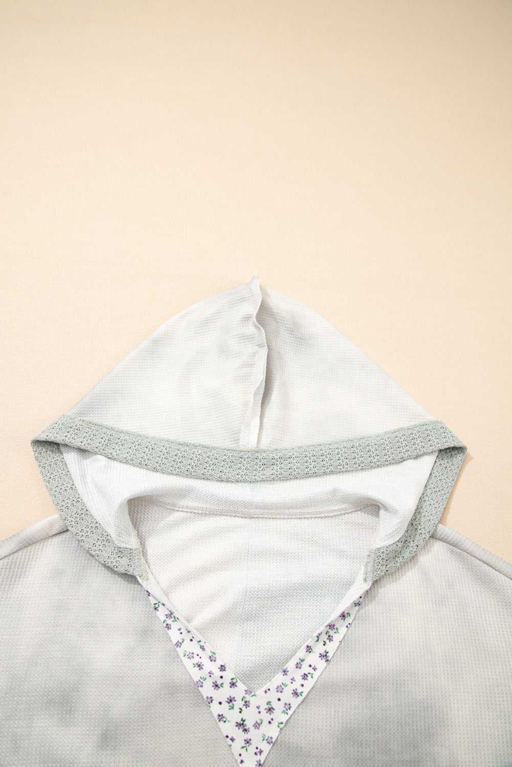 Light gray hoodie with floral pattern on a beige background