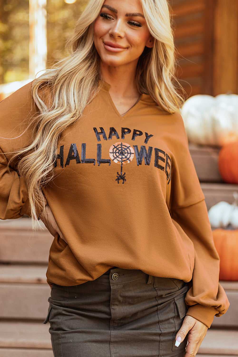 Close-up of chestnut Sequin Halloween Graphic Top featuring sparkling 'Happy Halloween' text and spider web design on V-neck.