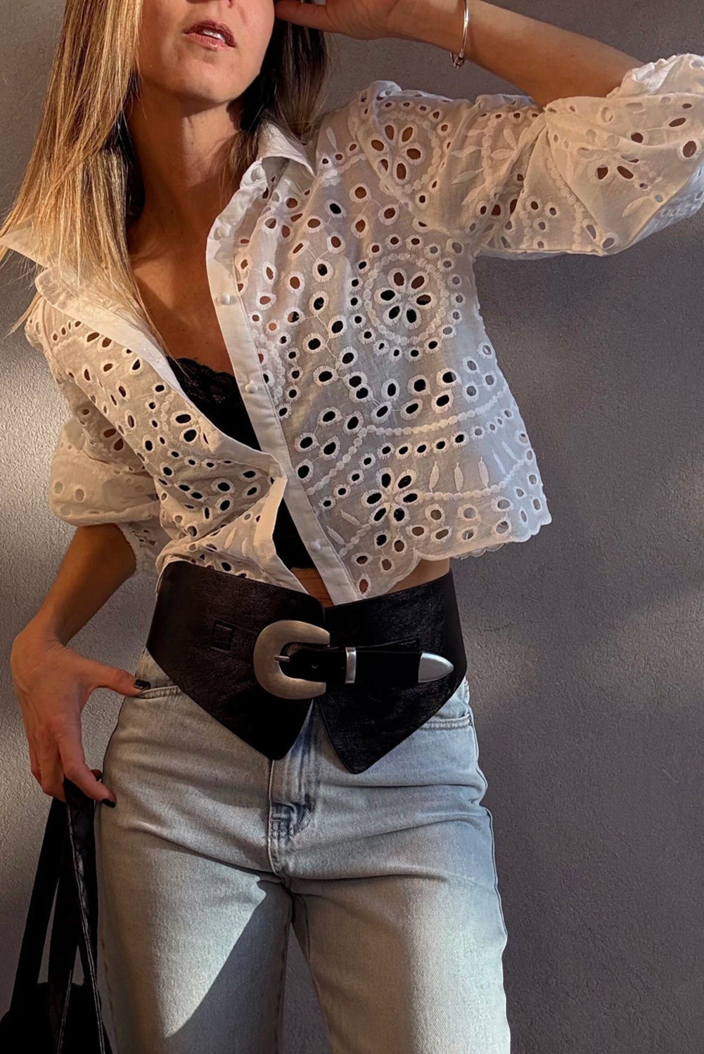 Person wearing a White Cutwork Embroidered Crop Top with black belt and jeans against a neutral background