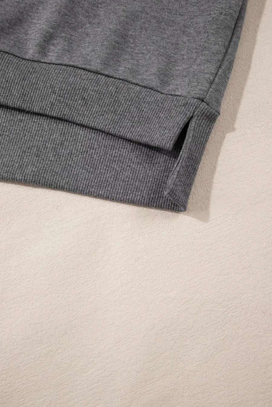Hem detail of gray zip-up sweatshirt dress with ribbed trim and side slit, ideal for a relaxed and stylish fit.