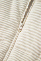 Close-up of zipper on beige corduroy puffer gilet, showcasing durable hardware and fine ribbed corduroy texture.