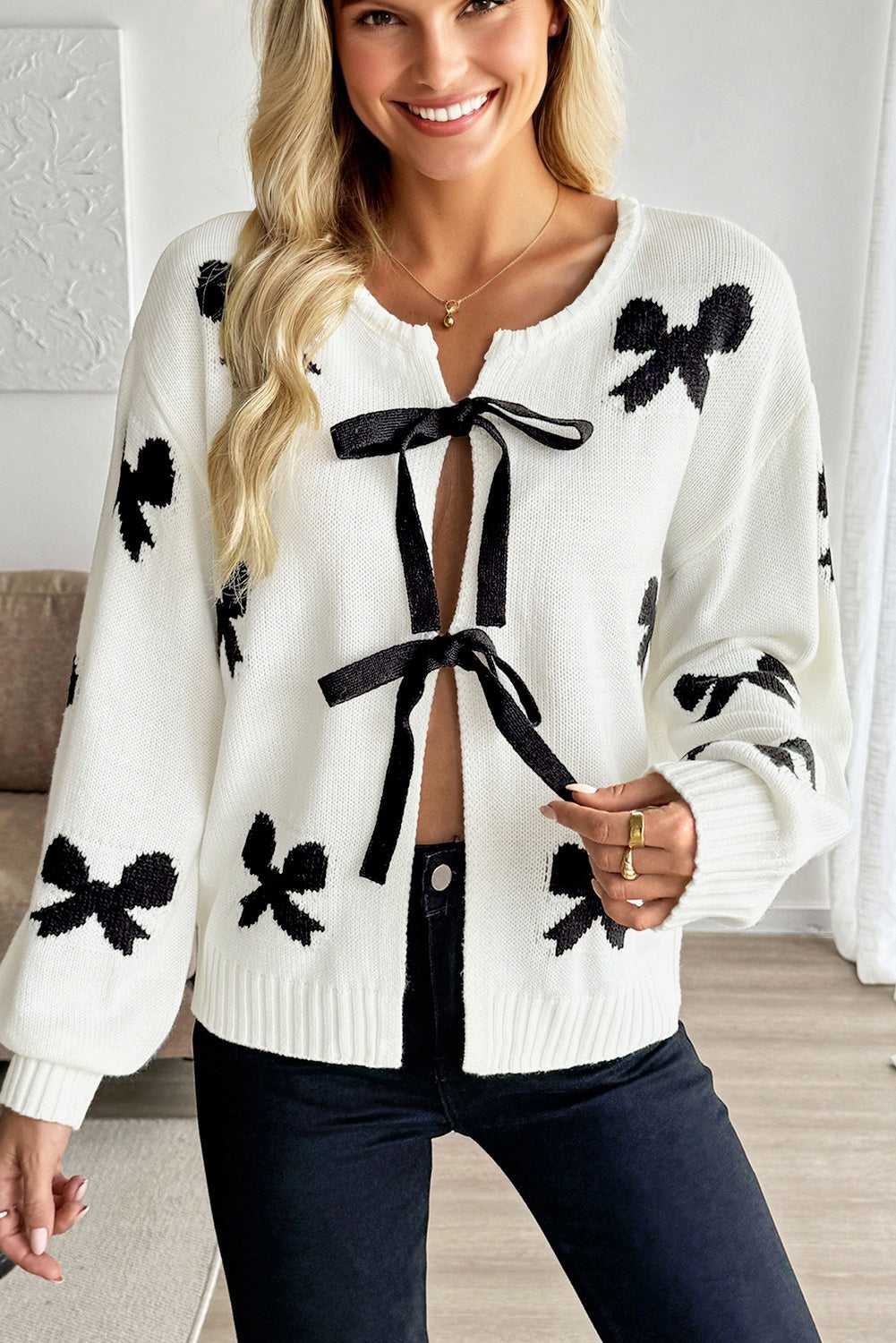 Women’s White Bow‑Lace Knit Cardigan featuring black bow patterns and ribbon tie closure, ideal for romantic spring or fall outfits.