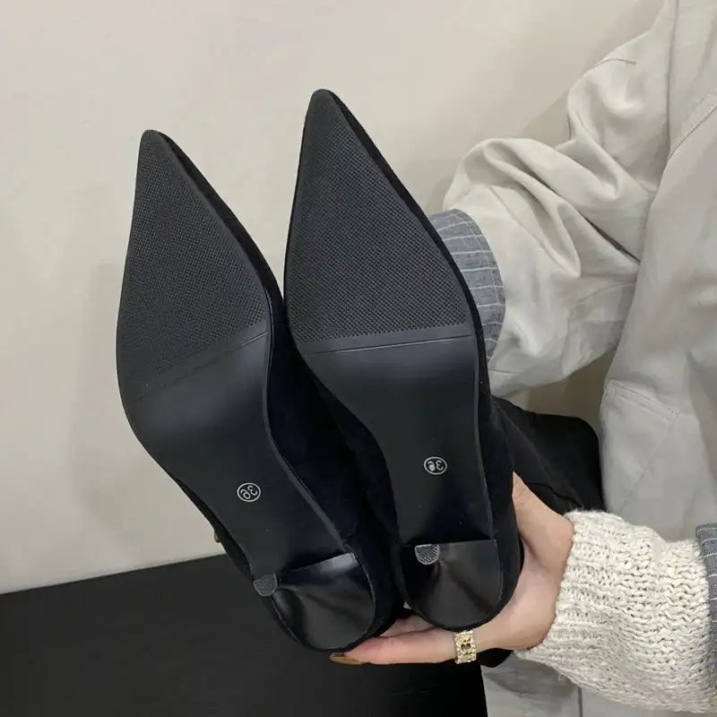 Close-up of black kitten heel boots showing textured sole and pointed toe, highlighting quality and grip design.