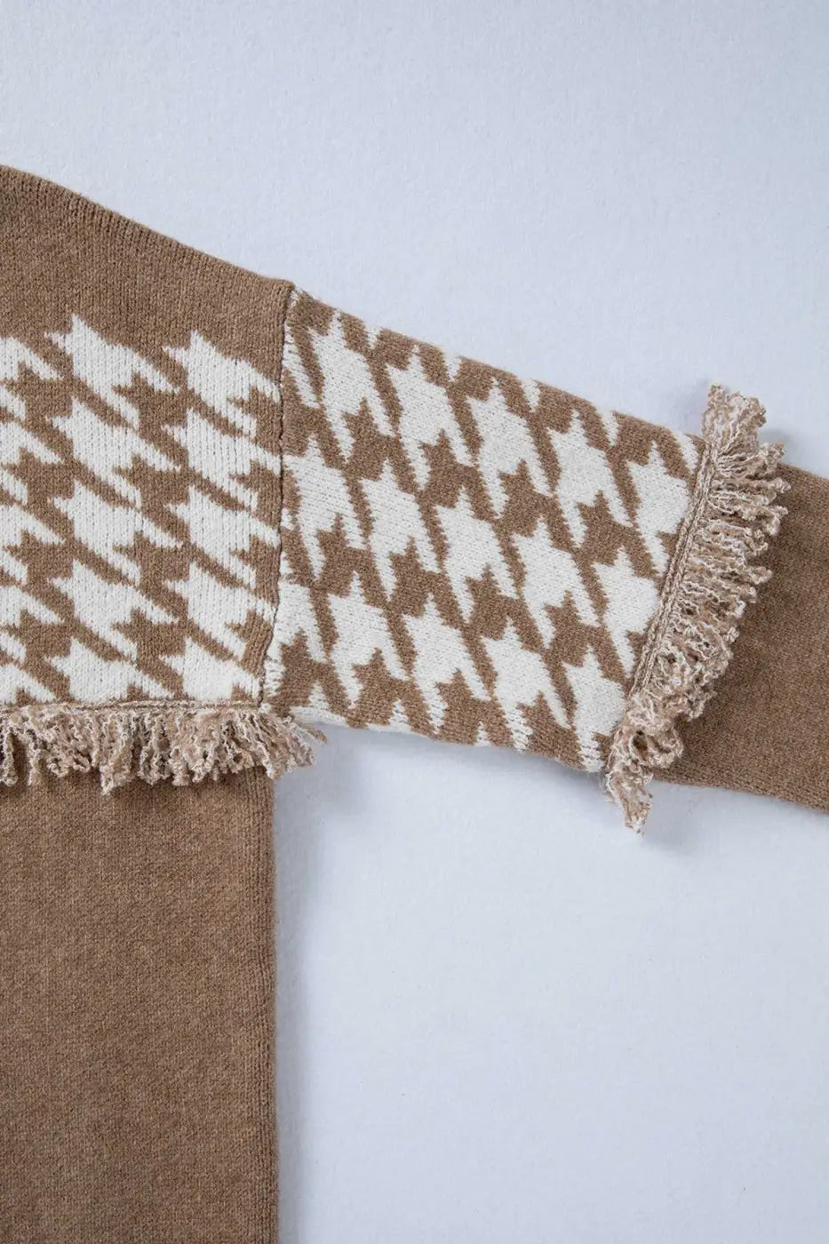 Sleeve detail of khaki houndstooth knit cardigan with fringe and white pattern. Designed for women’s stylish fall and autumn wear.