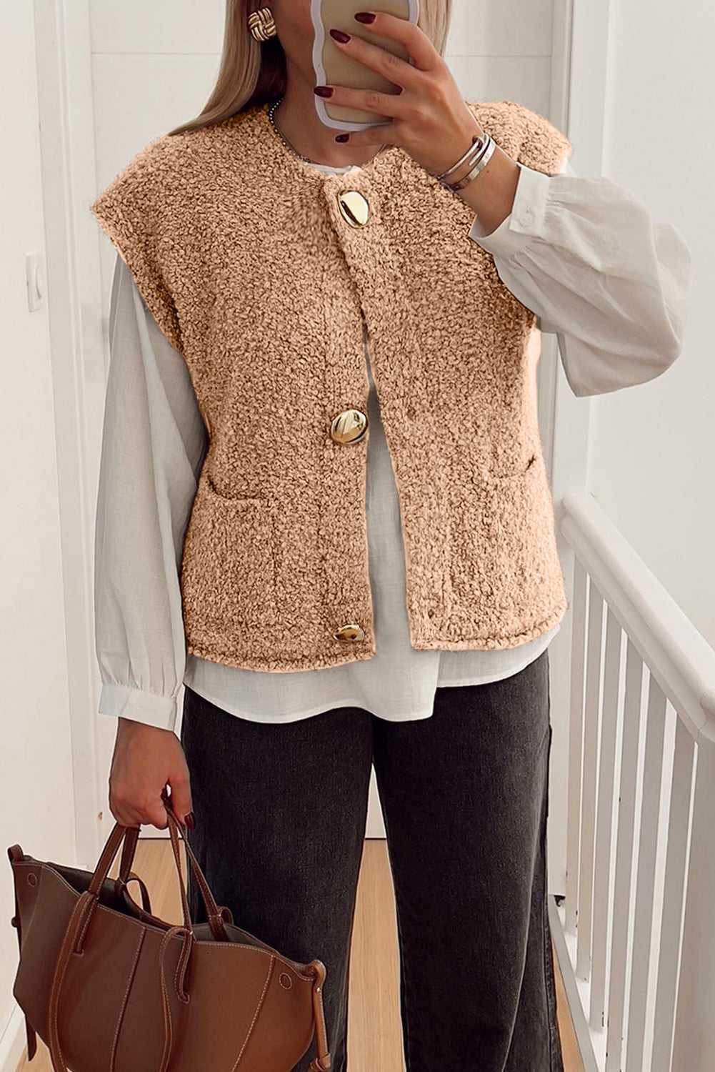 Cozy fleece gilet in beige with fuzzy texture, large button accents, and front pockets, styled over a white blouse and black jeans.