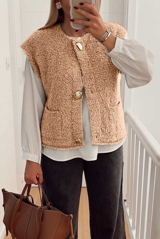 Cozy fleece gilet in beige with fuzzy texture, large button accents, and front pockets, styled over a white blouse and black jeans.