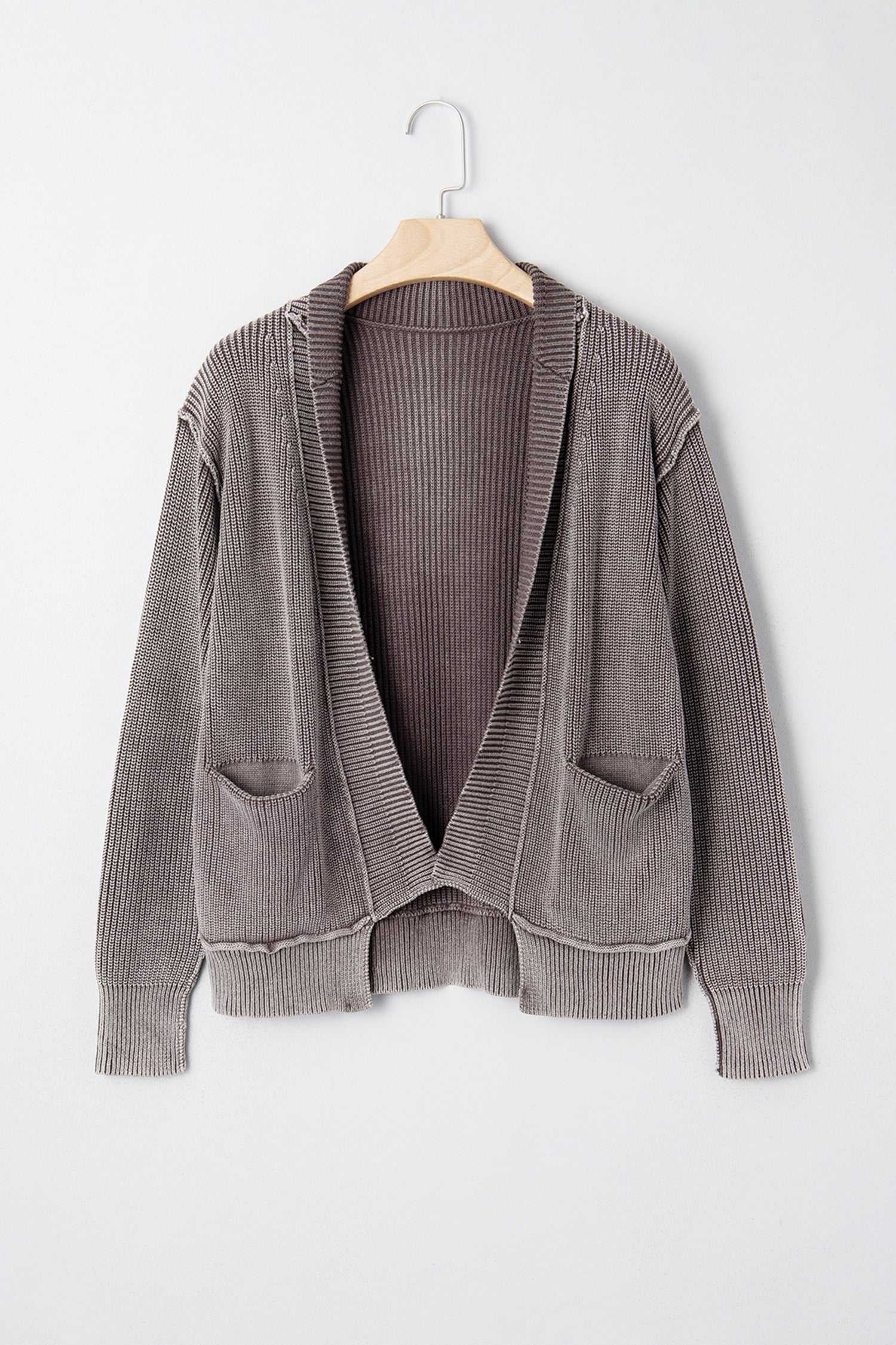 Brown stonewash patchwork knit open cardigan on hanger, featuring front pockets and ribbed knit texture, perfect for layering in fall.
