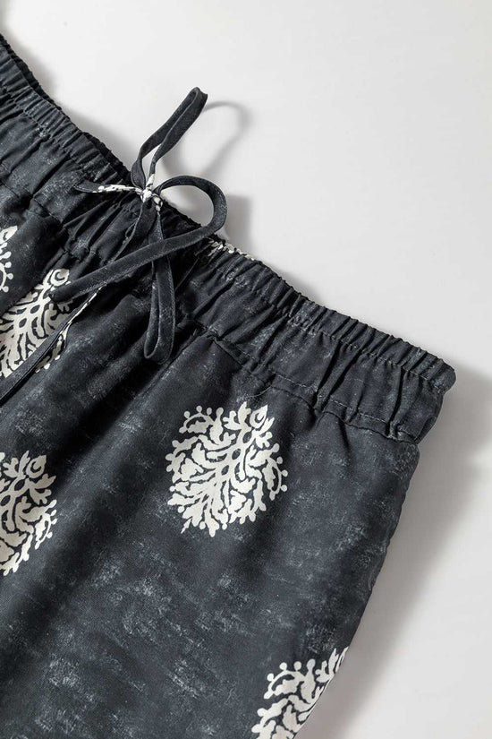 Close-up of waistband and drawstring on black geometric print wide leg trousers, showcasing elastic comfort and detailed white print.