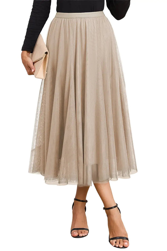 Person wearing a beige pleated skirt with black top and sandals indoors.