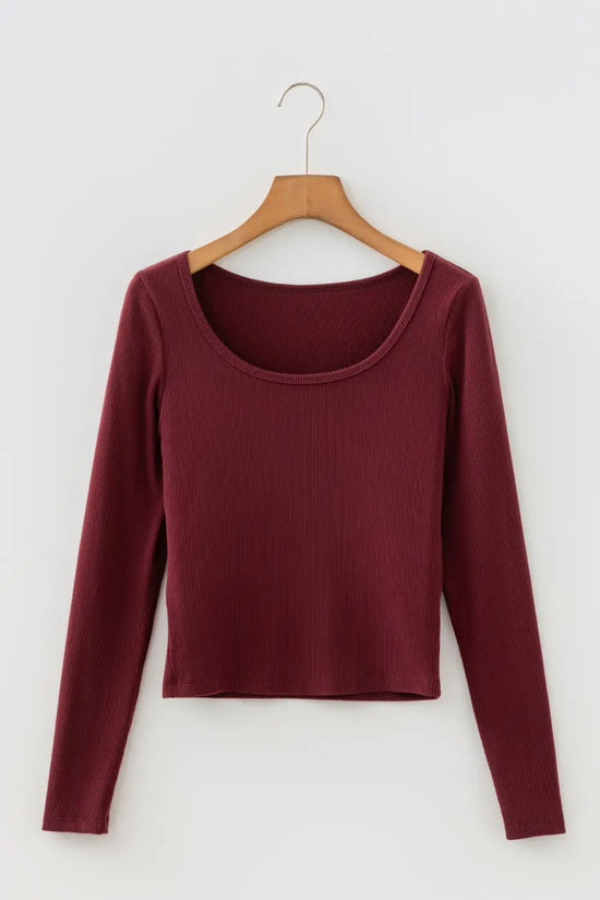 Brown ribbed long sleeve crop top on hanger showing scoop neckline and cropped hem. Lightweight knit ideal for layering basics.