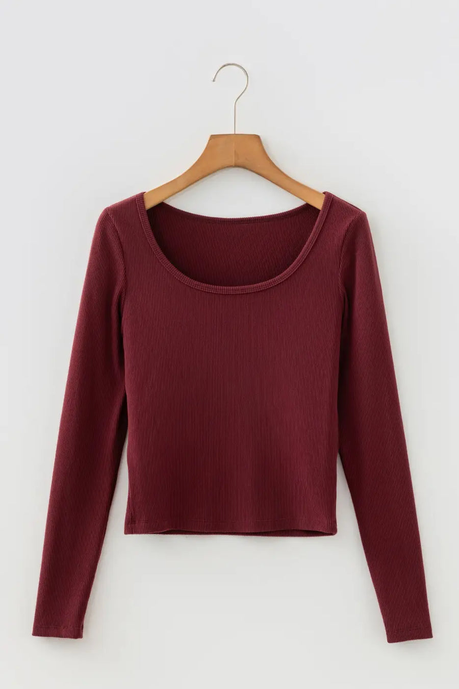 Brown ribbed long sleeve crop top on hanger showing scoop neckline and cropped hem. Lightweight knit ideal for layering basics.
