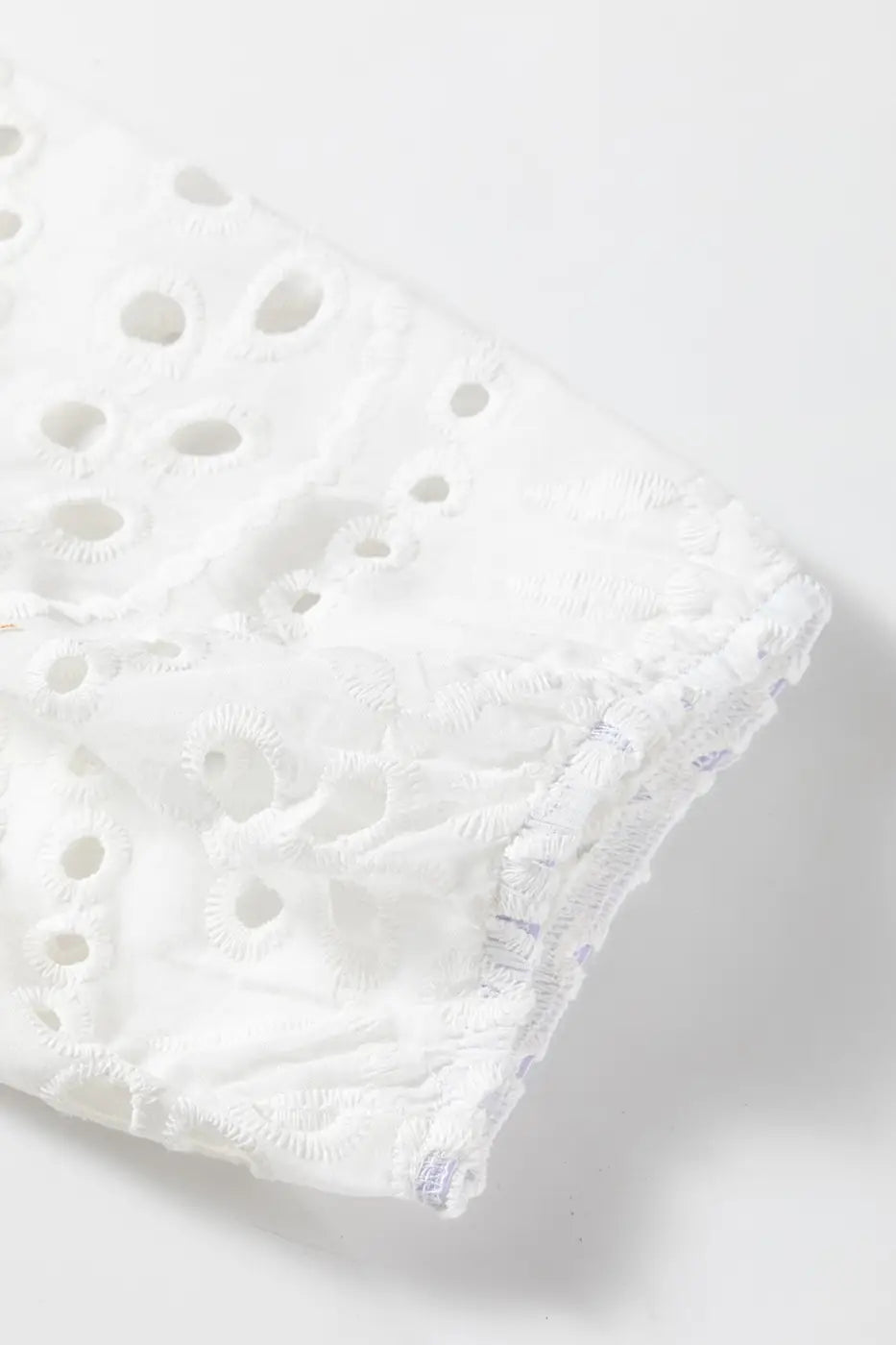 Detailed view of puff sleeve hem on White Cutwork Embroidered Crop Top, showcasing elastic finish and cutwork design.