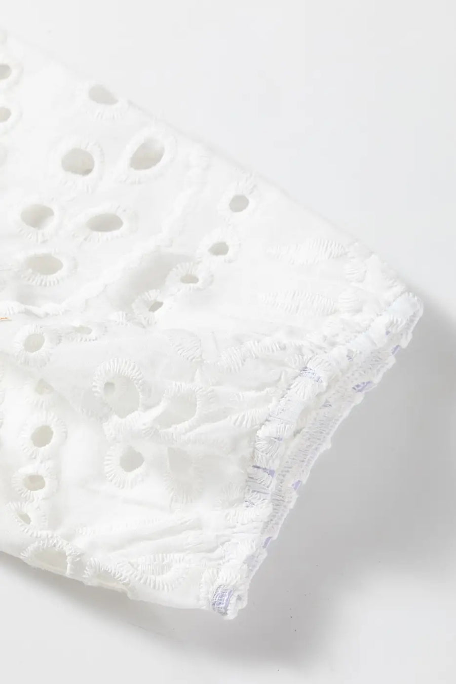 Detailed view of puff sleeve hem on White Cutwork Embroidered Crop Top, showcasing elastic finish and cutwork design.