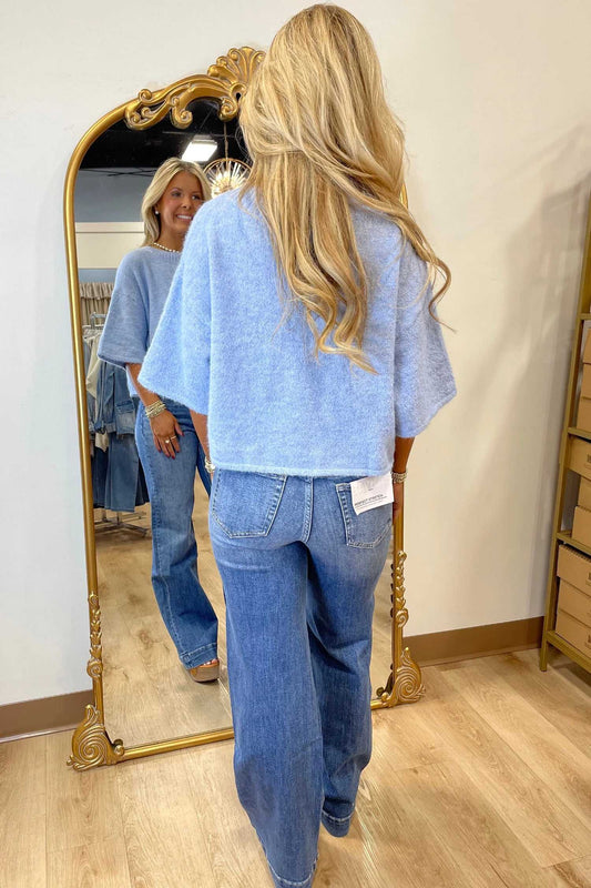 Back view of pastel blue fuzzy knit boxy cardigan with 3/4 sleeves, paired with wide-leg jeans for a relaxed outfit.
