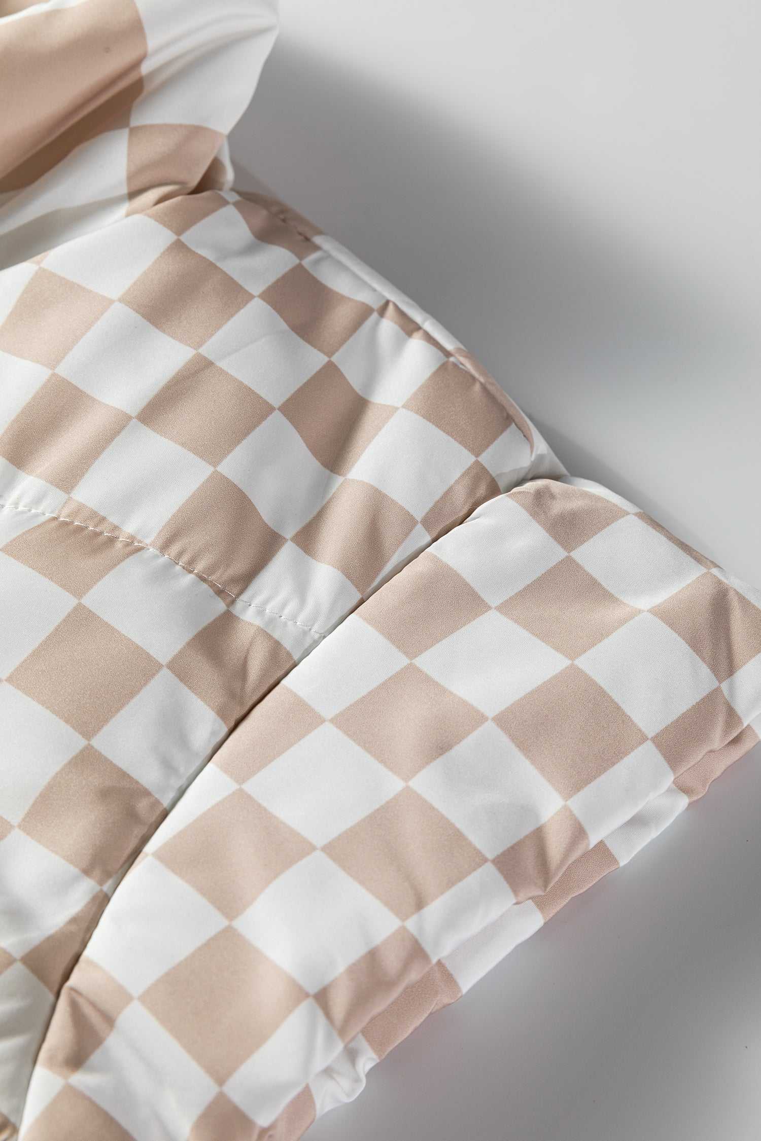 Detailed view of khaki plaid quilted fabric texture, emphasizing the soft, padded construction of this stylish winter vest.