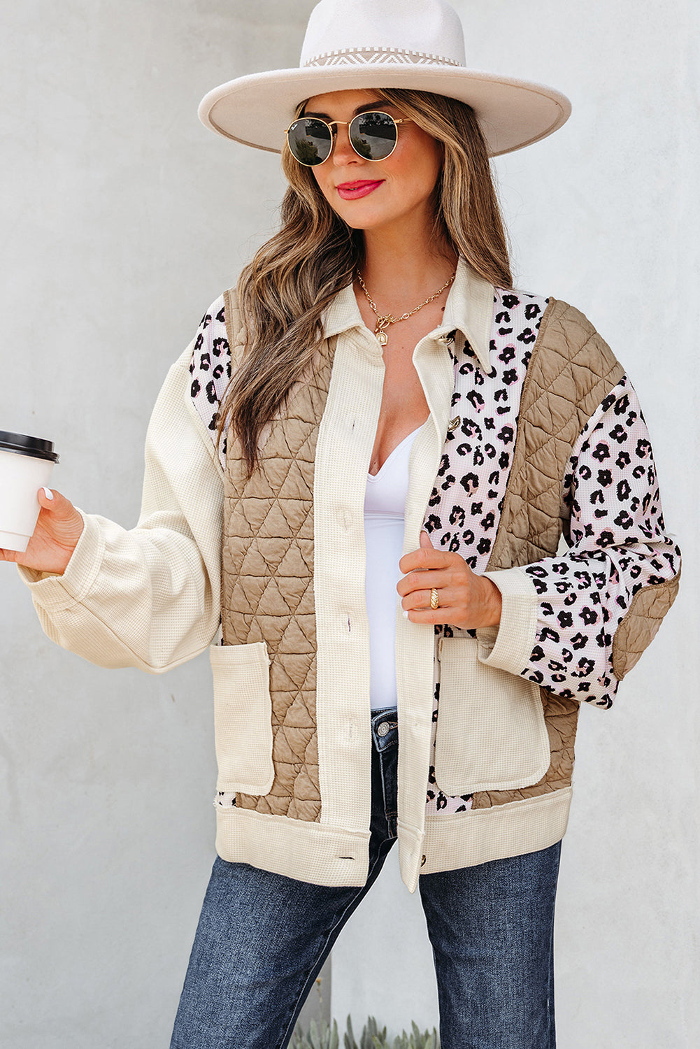 Woman wearing a beige quilted jacket with leopard print accents, holding a coffee cup.