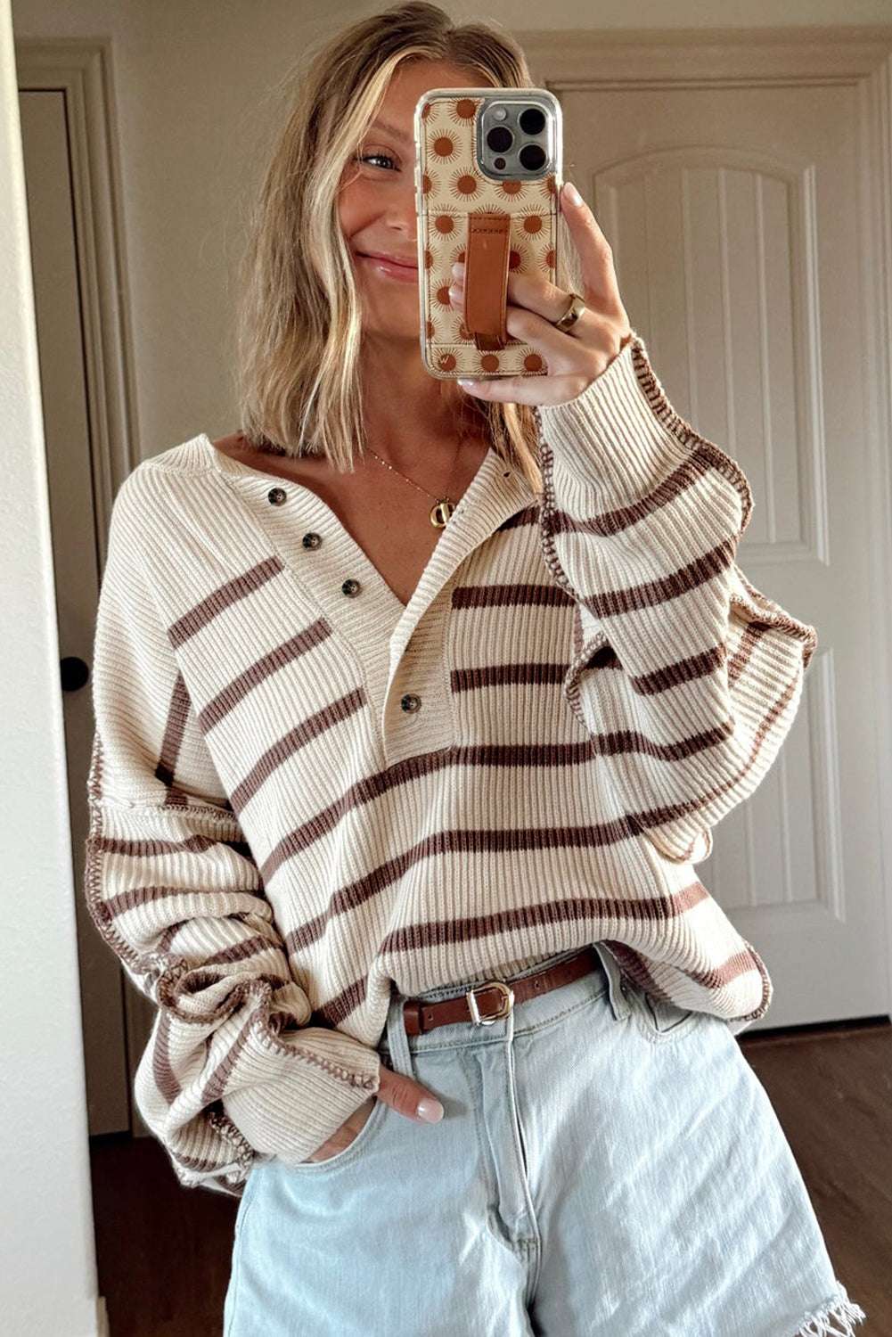Relaxed fit striped Henley jumper in beige and brown, paired with high-waisted denim shorts. Lightweight women’s knitwear for casual outfits.