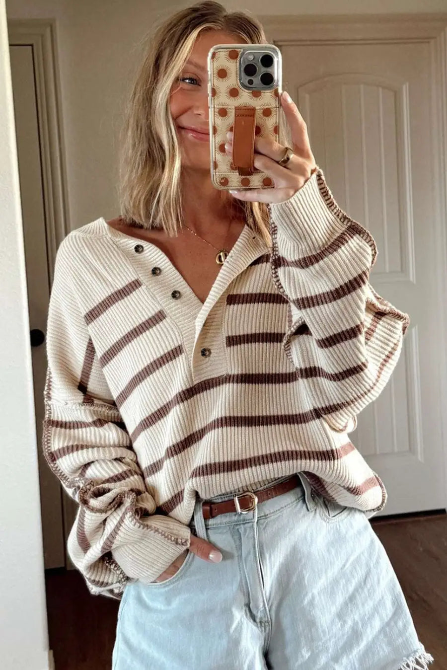Cream and brown striped Henley jumper with button front, worn with light denim shorts for a cozy casual outfit.