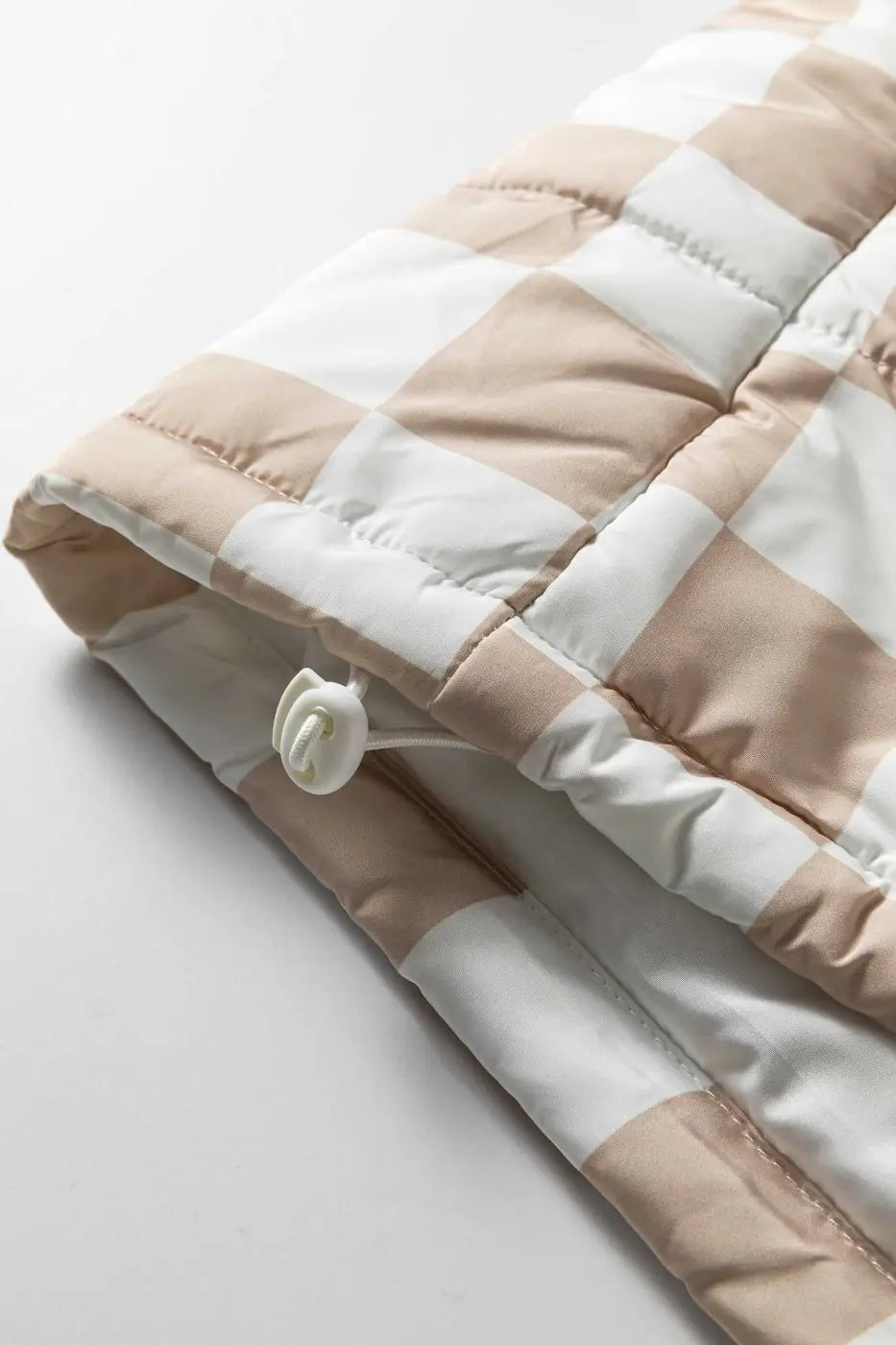 Close-up of adjustable drawcord hem on khaki plaid quilted gilet, designed for a snug fit and added warmth in winter.
