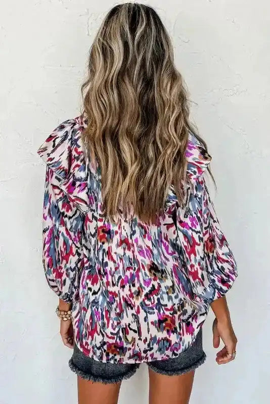 Back view of pink Abstract Ruffle Blouse with Puff Sleeves, showcasing colorful pattern and loose fit.