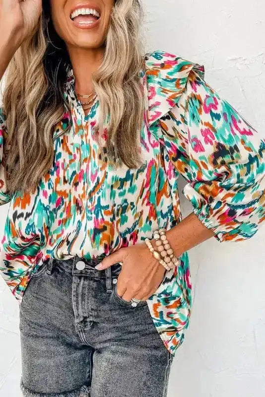 Abstract Ruffle Blouse with Puff Sleeves in teal and pink tones, styled with black denim shorts for a trendy outfit.