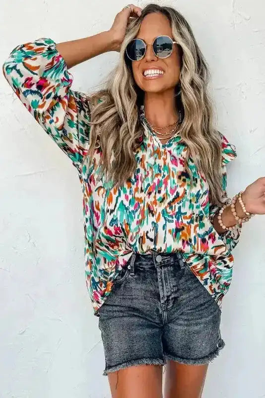 Abstract Ruffle Blouse with Puff Sleeves in multicolor print, styled with black shorts and sunglasses for a bold outfit.