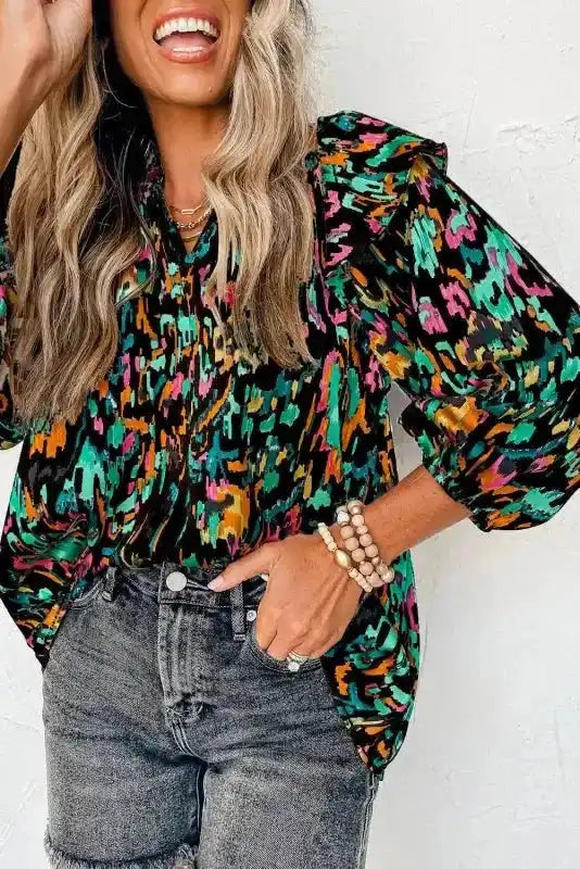 Model in black Abstract Ruffle Blouse with Puff Sleeves and vibrant print, paired with distressed jeans for a trendy look.
