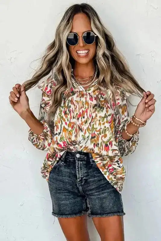 V-neck Abstract Ruffle Blouse with Puff Sleeves paired with black shorts, featuring a vibrant floral-inspired abstract design.
