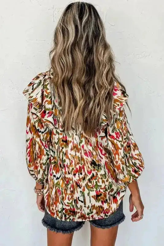 Back view of Abstract Ruffle Blouse with Puff Sleeves showing ruffle shoulder detail and colorful abstract pattern.