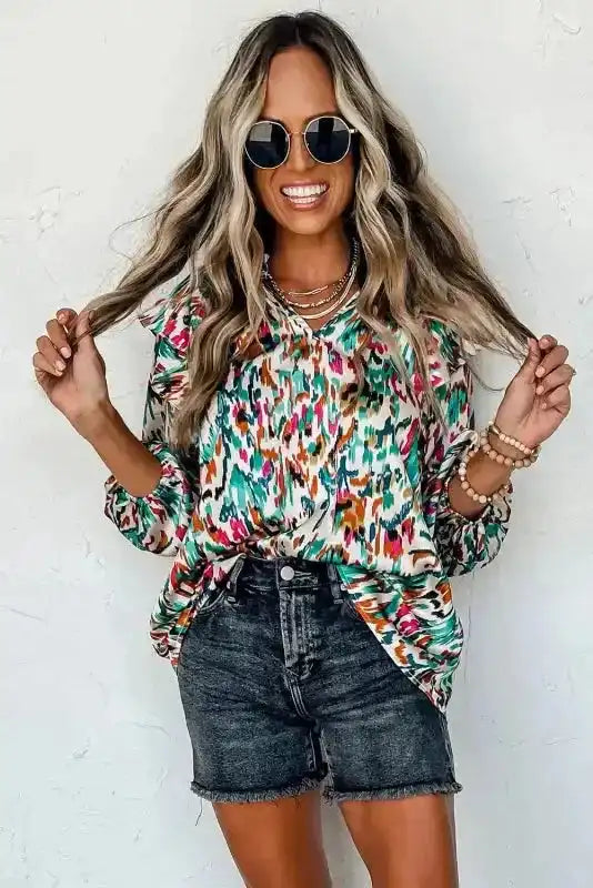 Smiling model wearing Abstract Ruffle Blouse with Puff Sleeves and black shorts, styled for a vibrant summer look.