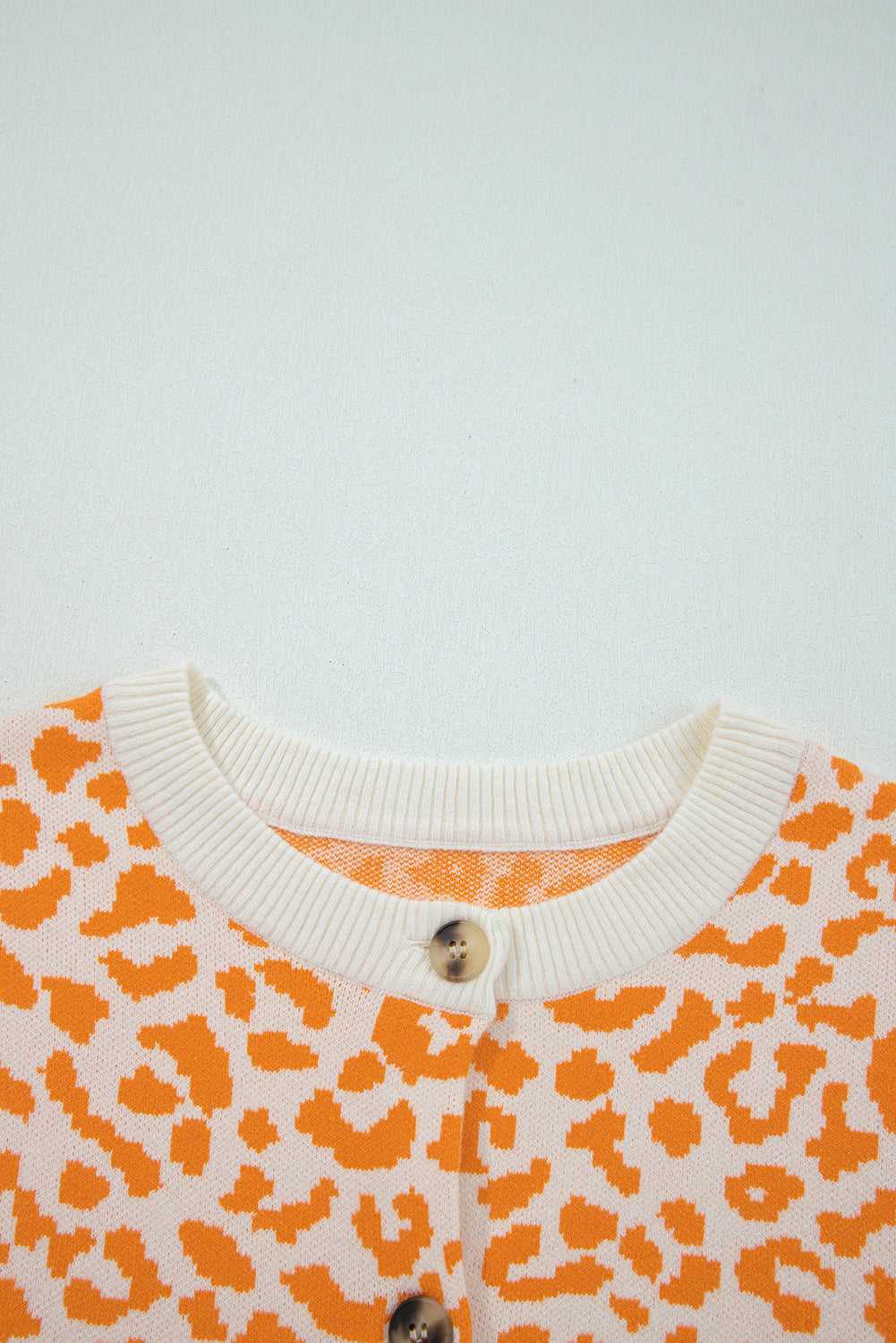 Orange chunky knit cardigan layered over neutral basics