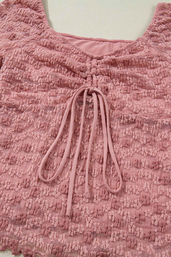 Detailed view of ruched front tie on pink floral lace blouse. Elegant lace fabric adds charm to this Southern Belle-style top.