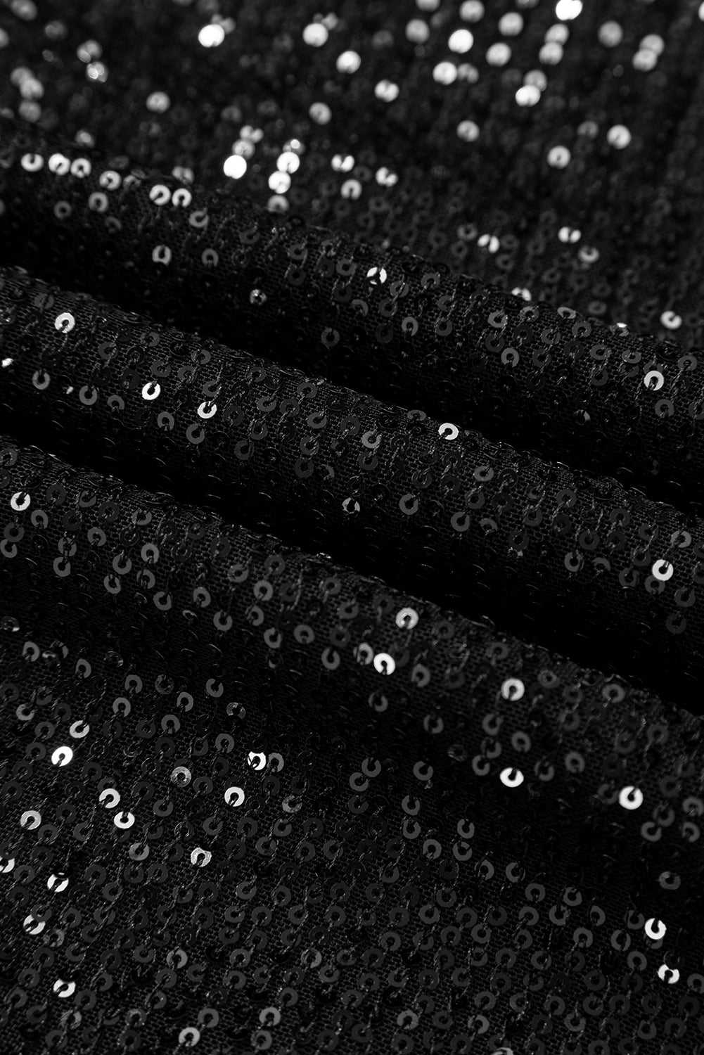 Close-up of black sequin fabric showing shimmering texture, used in elegant open back party tops for night out occasions.