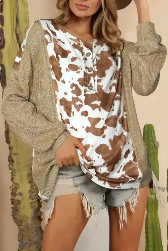 Animal Print Textured Henley Blouse with brown and white cow print front, ribbed knit sleeves, and button neckline, styled with denim shorts.