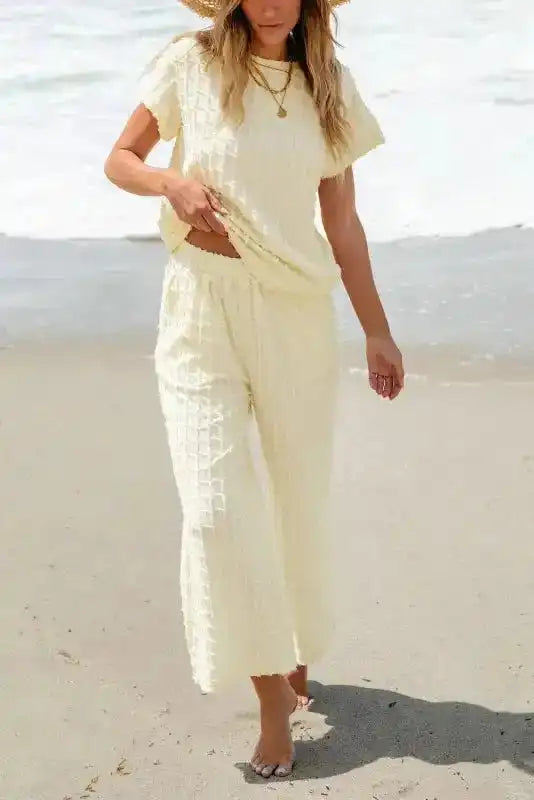 Model walking on beach in Apricot Lattice Two Piece Set, featuring soft flared pants and casual top.